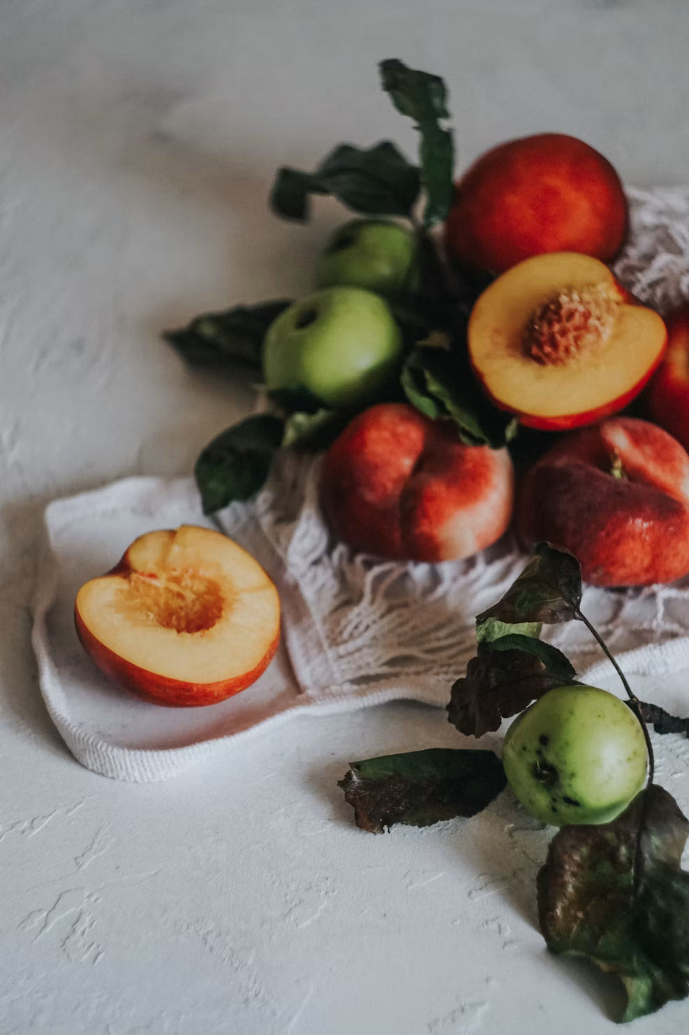 Summer breakfast table with ripe fruit, linen textiles and warm morning light representing the Fruity Home Fragrance Collection by Glim & Glam.