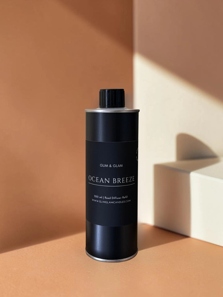 Glim & Glam Ocean Breeze 200ml reed diffuser refill bottle in a sleek black metal container on a warm beige background.